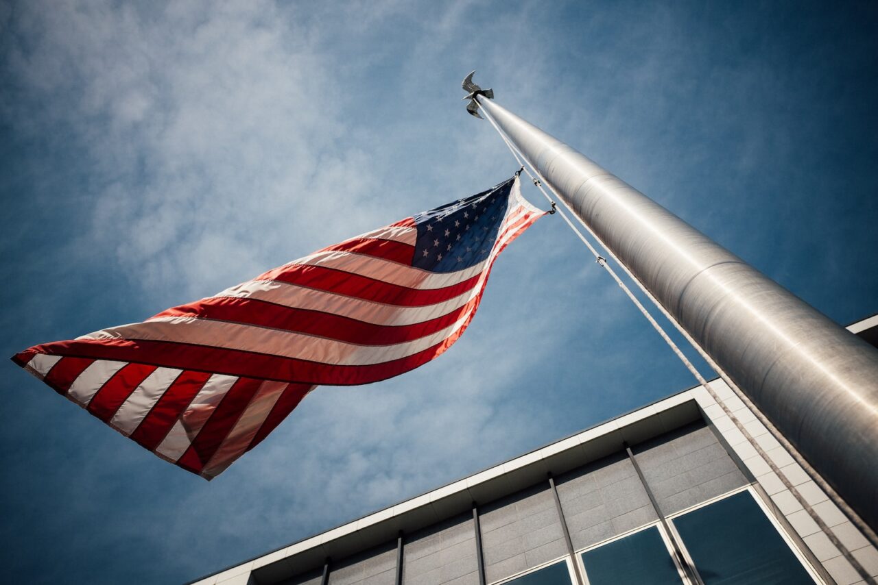 low-angle photo of U.S. flag placed on gray pole